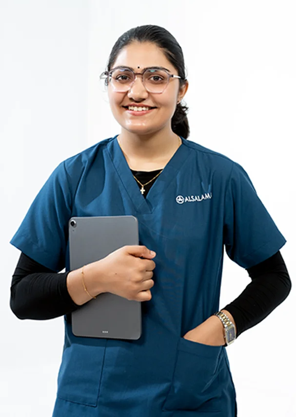 Smiling ophthalmology student in blue scrubs holding a tablet, representing digital learning, clinical training, and modern healthcare education at Alsalama